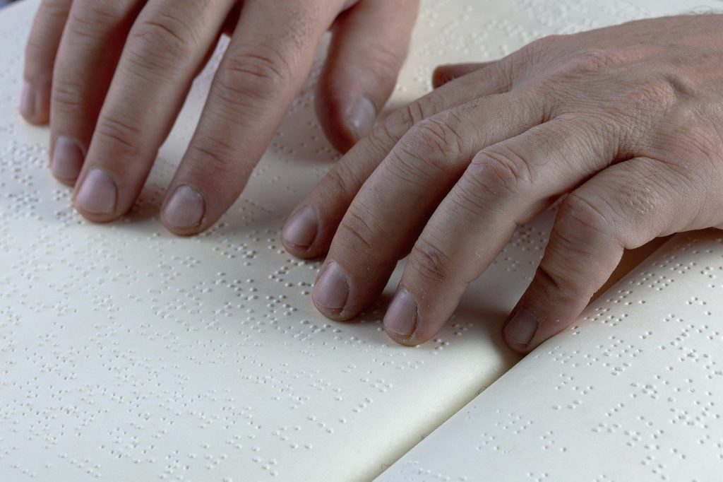 Hands reading braille book